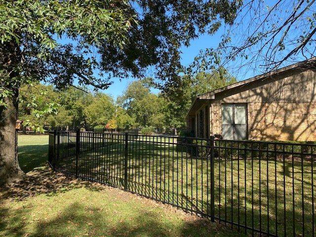 A house with a black fence and a tree in front of it.