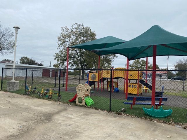 A playground with umbrellas and a fence around it