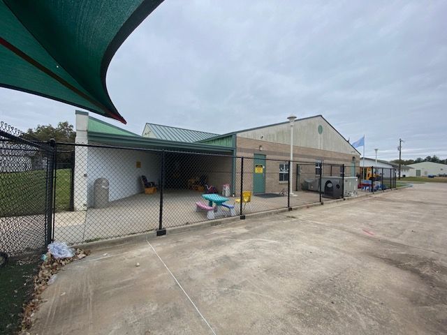 A fenced in area with a picnic table in front of a building.