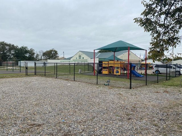 A playground with a green umbrella and a slide.
