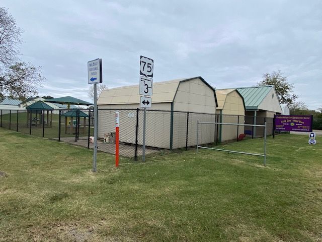A fenced in area with a building and a sign that says 75 on it.