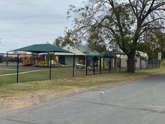A park with a playground and a fence around it