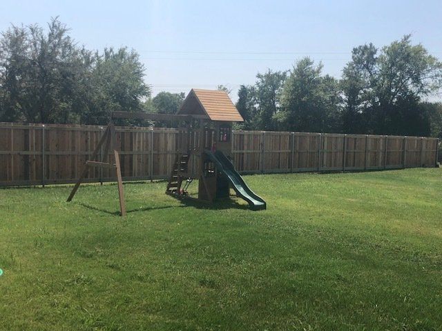 A backyard with a playground and a wooden fence.