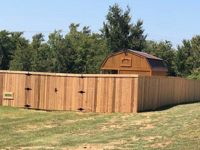 A wooden fence surrounds a barn in a grassy field.