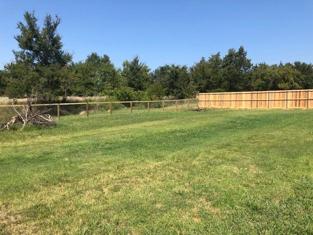A large grassy field with a wooden fence in the background