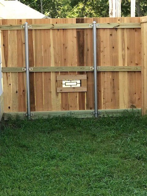 A wooden fence is sitting in the middle of a lush green yard.