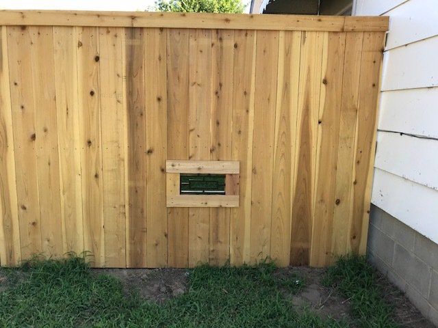 A wooden fence with a small window in the middle of it.