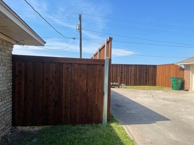 A wooden fence surrounds a driveway in front of a house.