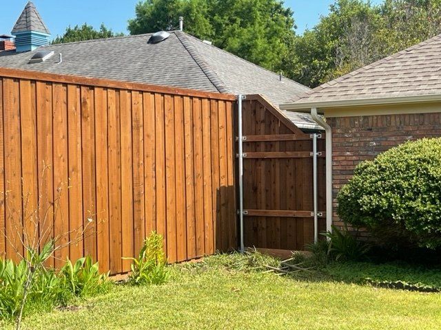 A wooden fence is in the backyard of a house.
