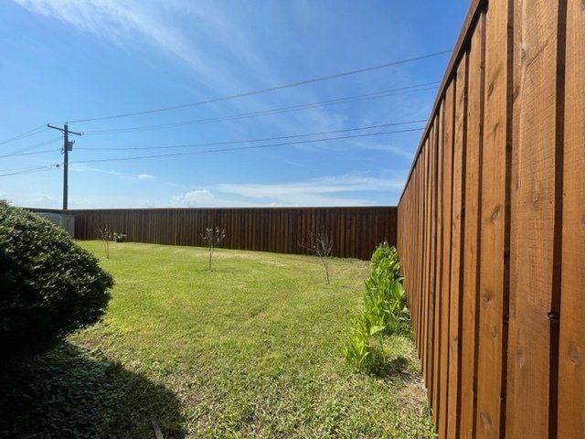 A wooden fence surrounds a lush green yard.