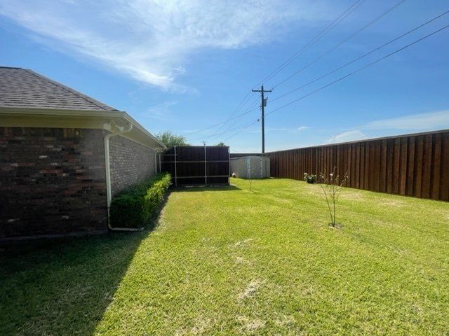 A backyard with a fence and a house in the background.