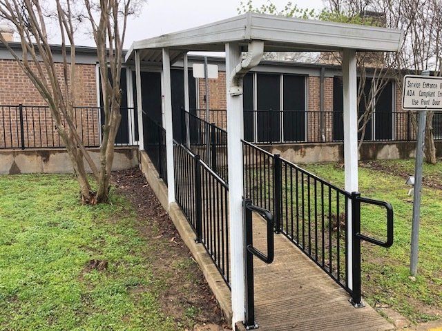 A handicapped ramp leading to a building with a sign on the side of it.