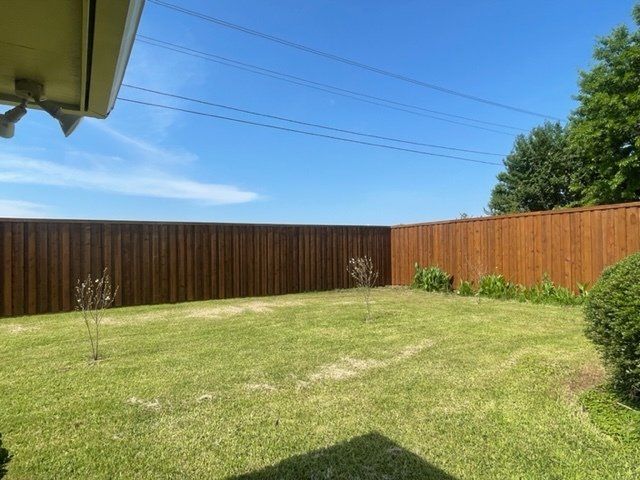 A backyard with a wooden fence and a lush green lawn.
