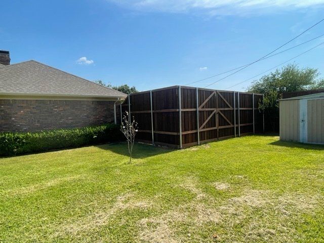 A house with a fence and a shed in the backyard
