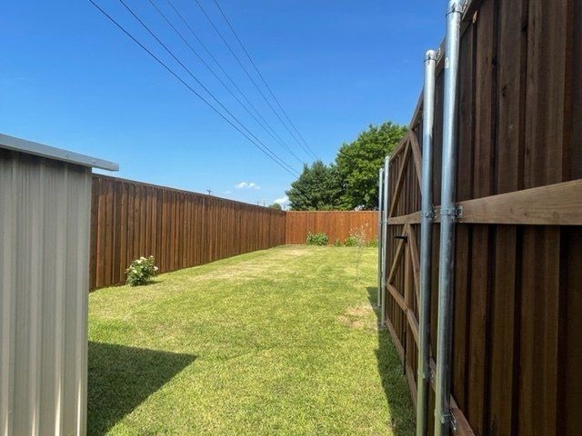 A backyard with a wooden fence and a metal shed