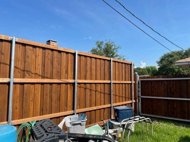 A wooden fence is in the backyard of a house.