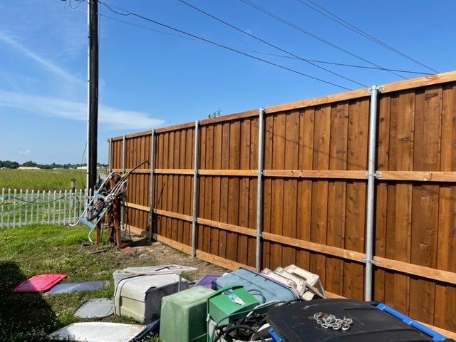 A wooden fence is surrounded by luggage in a backyard.