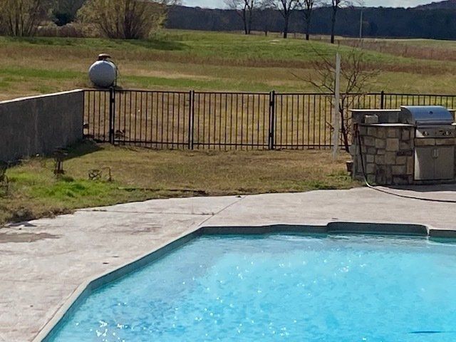 A large swimming pool with a grill in the backyard