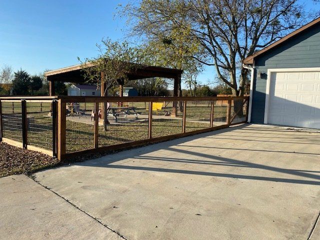 A wooden fence is surrounding a driveway next to a garage.