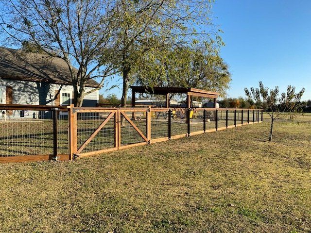 A wooden fence is in the middle of a grassy field.