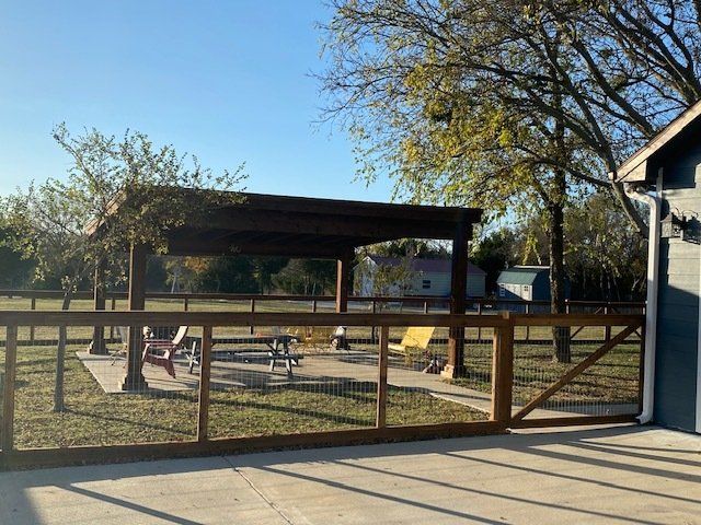 A wooden fence surrounds a picnic area with tables and chairs.