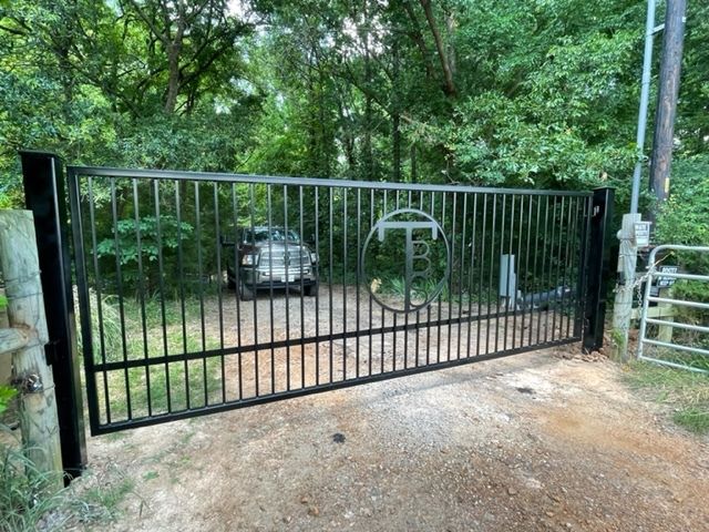 A car is parked in a driveway behind a black gate.