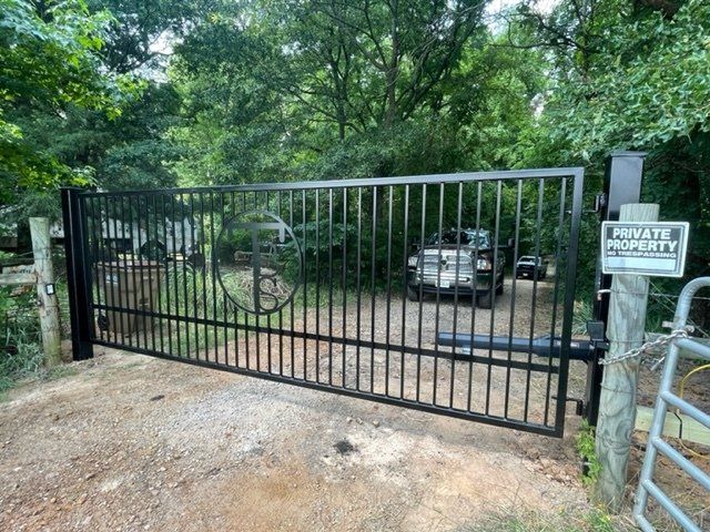 A car is parked in a driveway behind a gate that says private security.