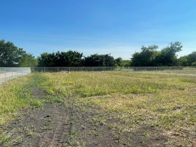 An empty field with a fence and trees in the background
