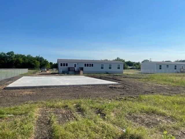 A large white building is sitting in the middle of a grassy field.