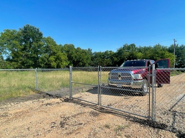 A red truck is parked in front of a chain link fence.