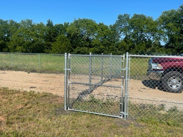 A red truck is parked behind a chain link fence