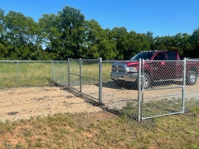 A red truck is parked behind a chain link fence.