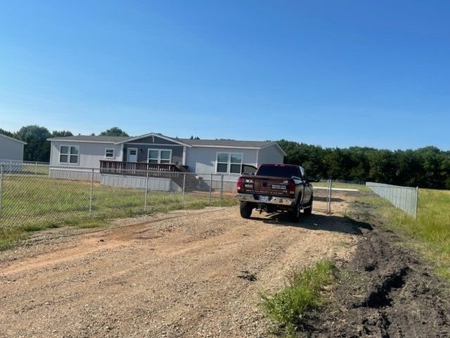 A truck is parked on a dirt road in front of a house