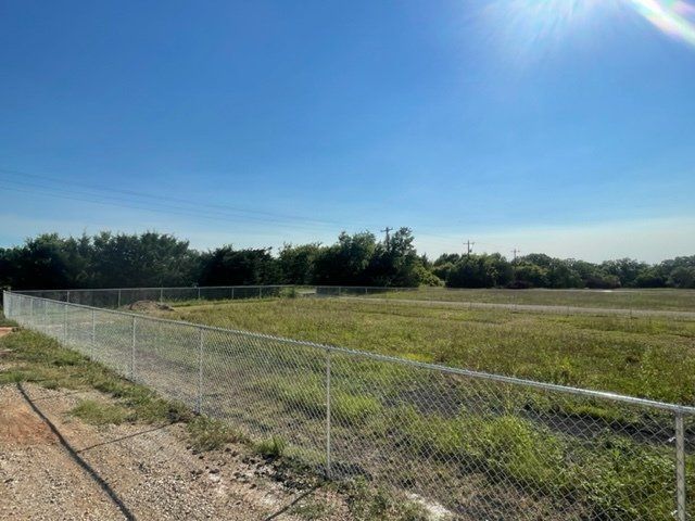 A chain link fence surrounds a large grassy field.