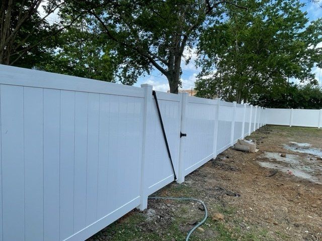 A white fence with a hose attached to it in a yard.