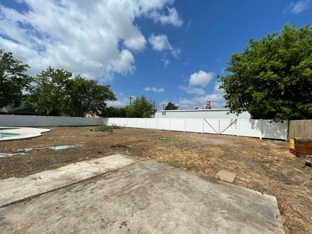 A backyard with a pool and a white fence