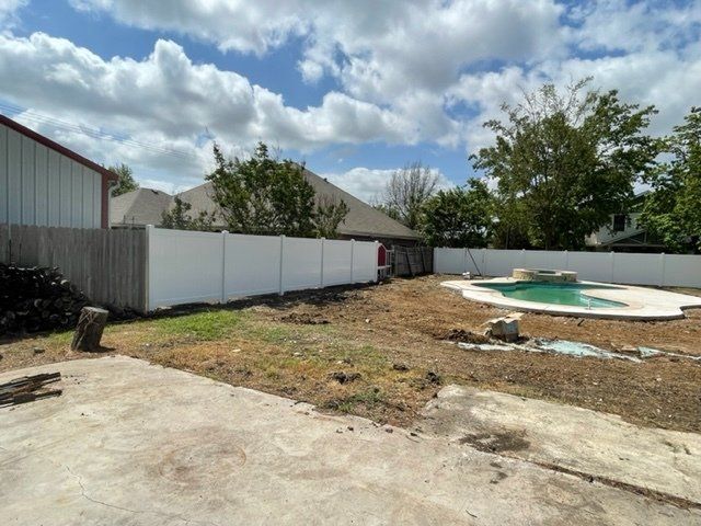 A backyard with a pool and a white fence