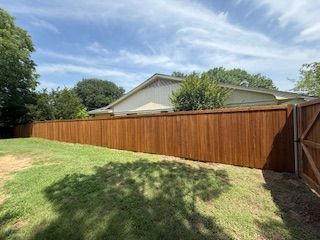 A wooden fence is in the backyard of a house.