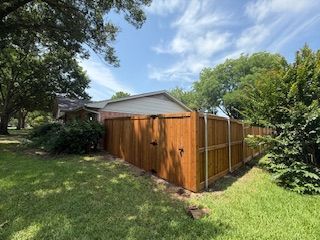 A wooden fence is in the backyard of a house.