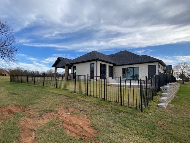 The back of a house with a black fence around it.