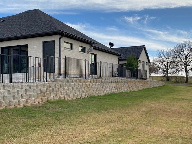 A house with a fence around it and a large lawn in front of it.