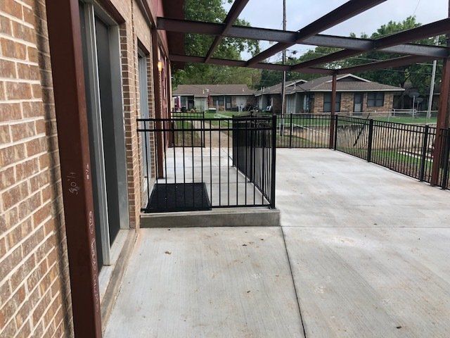 A brick building with a patio and a metal railing