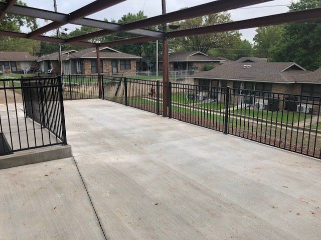A concrete patio with a metal railing surrounded by houses