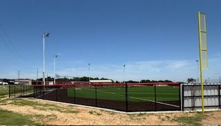 A baseball field with a fence around it and a blue sky in the background.