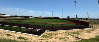 A baseball field with a fence around it on a sunny day.