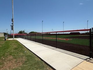 A baseball field with a fence around it and a walkway leading to it.