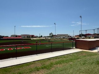A baseball field with a fence and a walkway leading to it.
