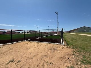 A baseball field with a fence around it and a building in the background.