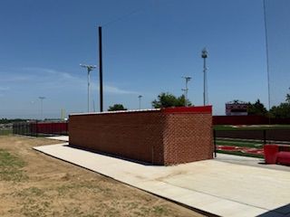 There is a brick building in the middle of a field.
