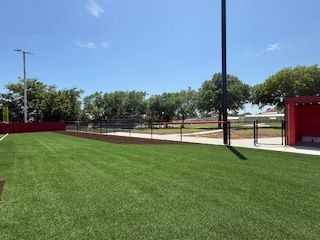 A baseball field with a red dugout in the background